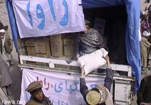 A RAWA member distributes bags of flour